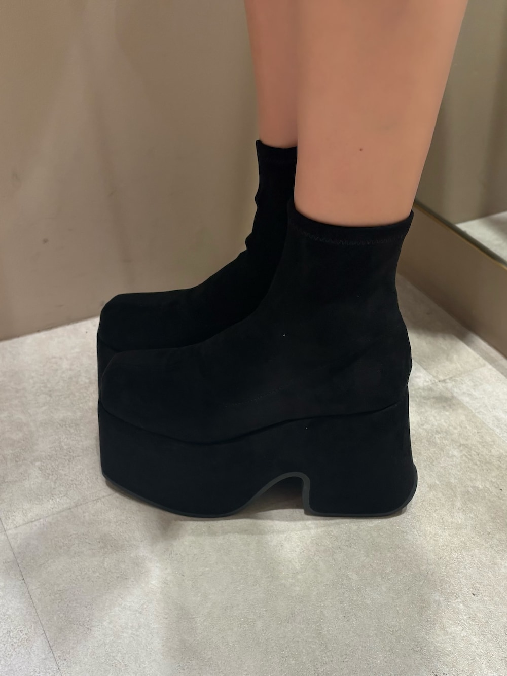 ブラック系のニット/セーター、グレー系のスカート、ブラック系のブーツを着用したレディースの春コーディネートの5枚目の写真