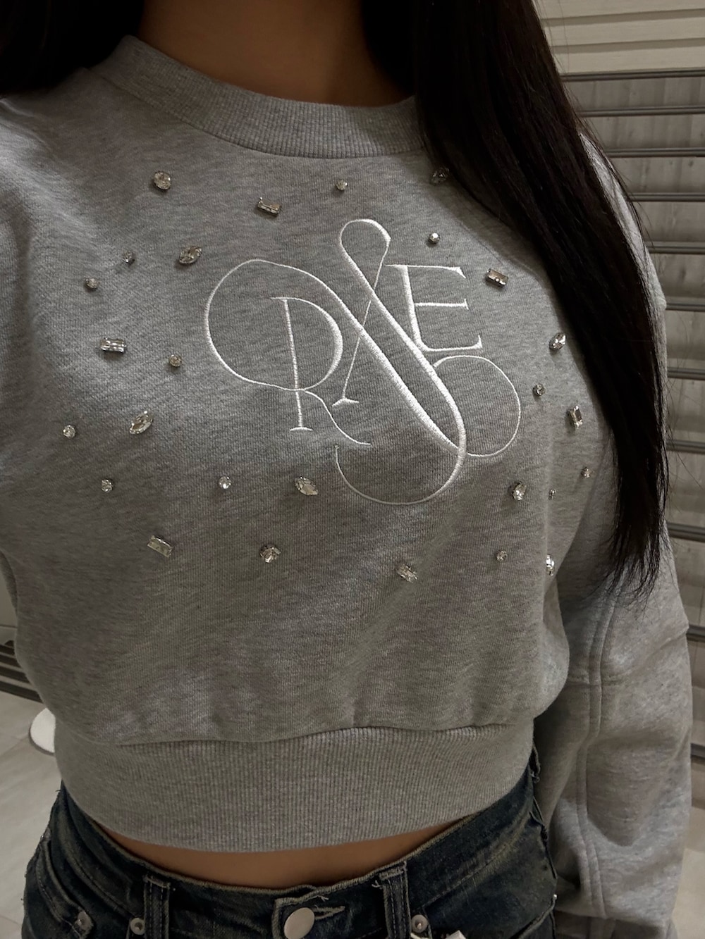 グレー系のスウェット、ブルー系のデニムパンツ、ブラック系のブーツを着用したレディースの冬コーディネートの4枚目の写真