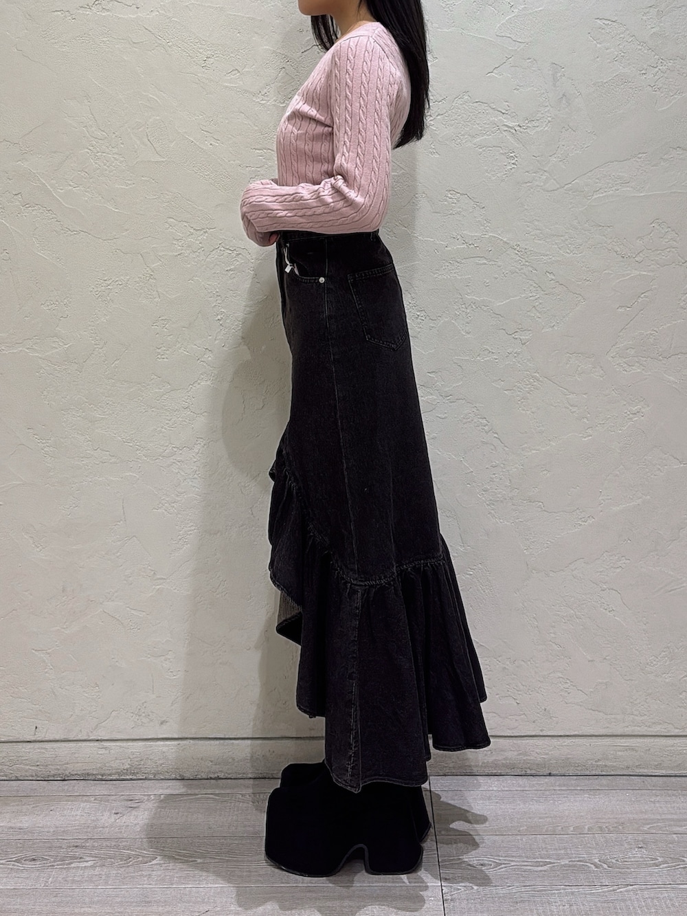 ピンク系のニット/セーター、ブラック系のデニムスカート、ブラック系のブーツを着用したレディースの秋コーディネートの2枚目の写真