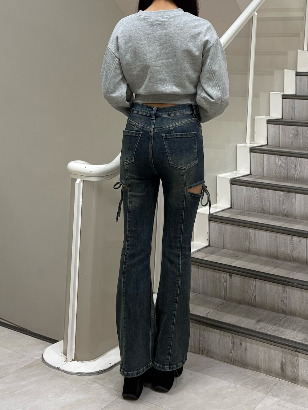 グレー系のスウェット、ブルー系のデニムパンツ、ブラック系のブーツを着用したレディースの冬コーディネートの3枚目の写真