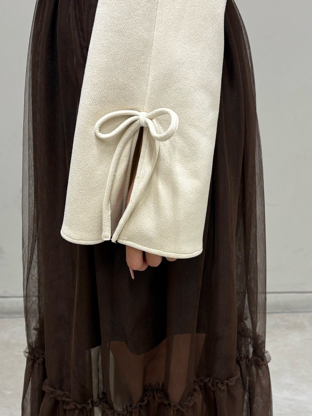 ホワイト系のブルゾン、ブラウン系のスカート、ブラック系のブーツを着用したレディースの春コーディネートの4枚目の写真