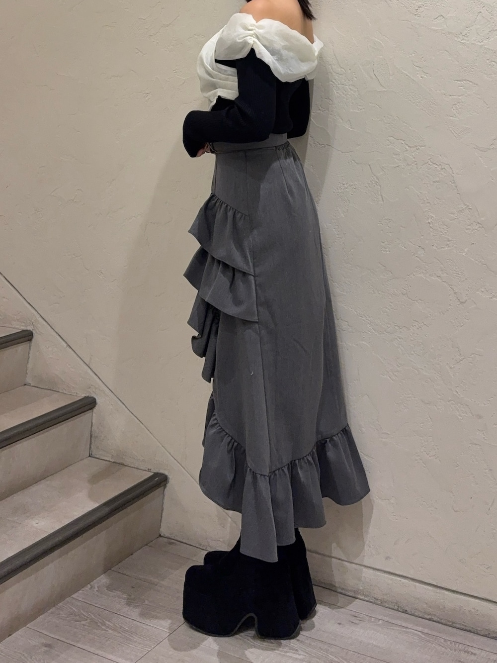 ブラック系のニット/セーター、グレー系のスカート、ブラック系のブーツを着用したレディースの春コーディネートの2枚目の写真