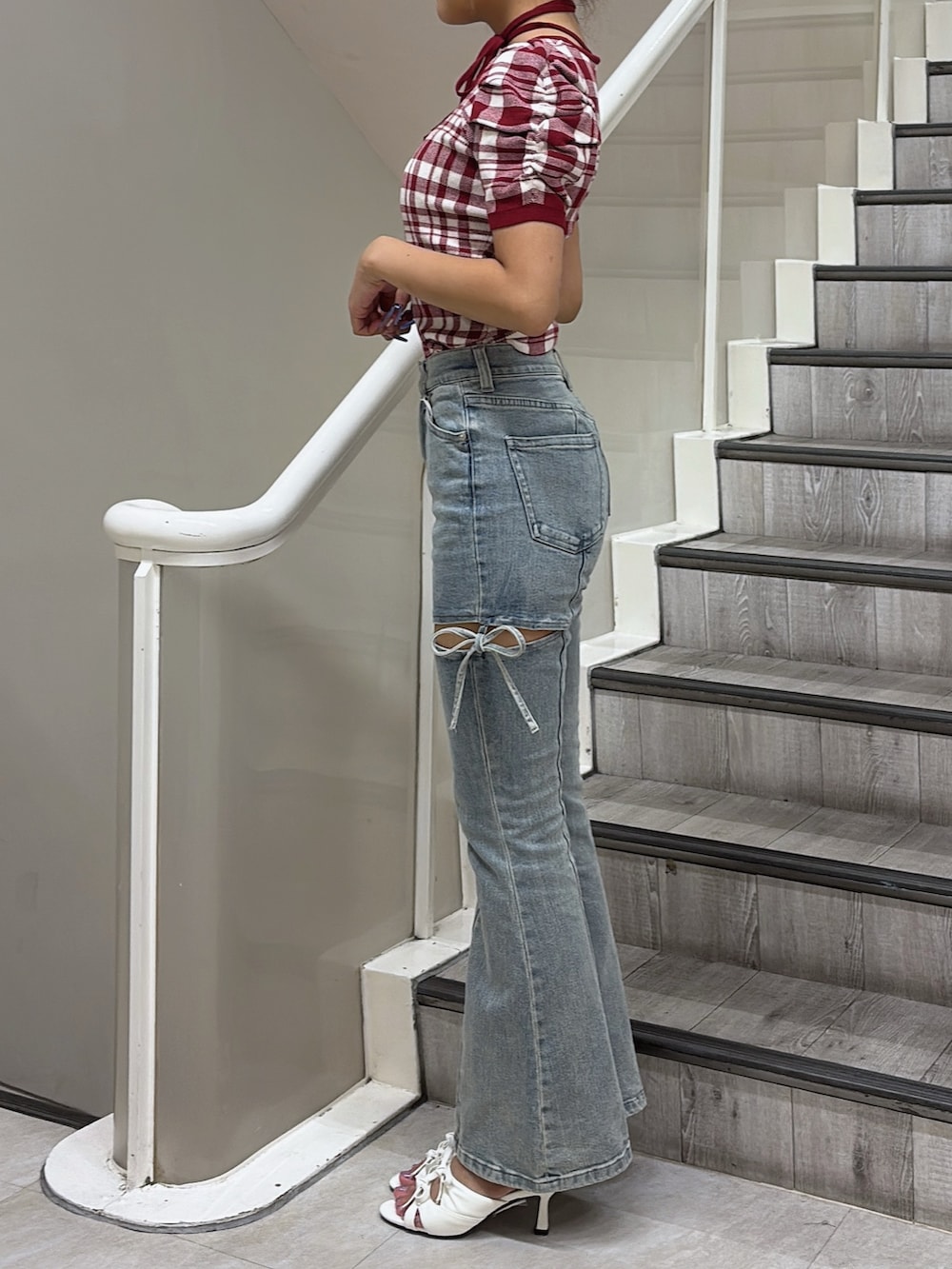 レッド系のニット/セーター、ブルー系のデニムパンツ、ホワイト系のサンダルを着用したレディースの夏コーディネートの2枚目の写真