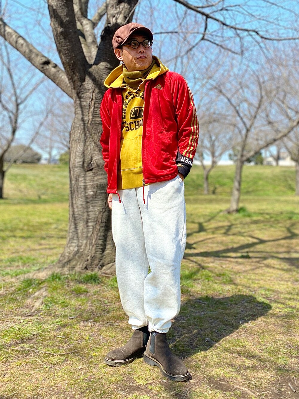 レッド系のジャージ、ホワイト系のスウェットパンツ、ブラウン系のブーツを着用したメンズの春コーディネートの2枚目の写真