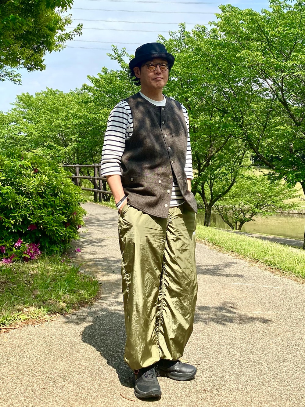 ブラック系のベスト、グリーン系のその他パンツ、ブラック系のスニーカーを着用したメンズの春コーディネートの2枚目の写真