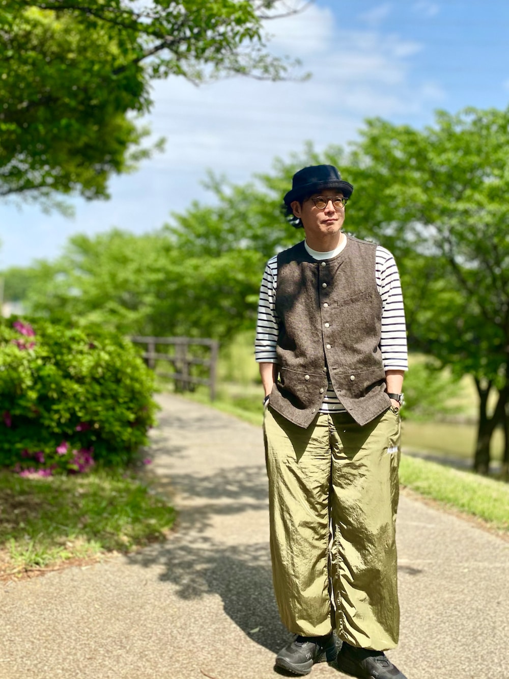 ブラック系のベスト、グリーン系のその他パンツ、ブラック系のスニーカーを着用したメンズの春コーディネートの3枚目の写真