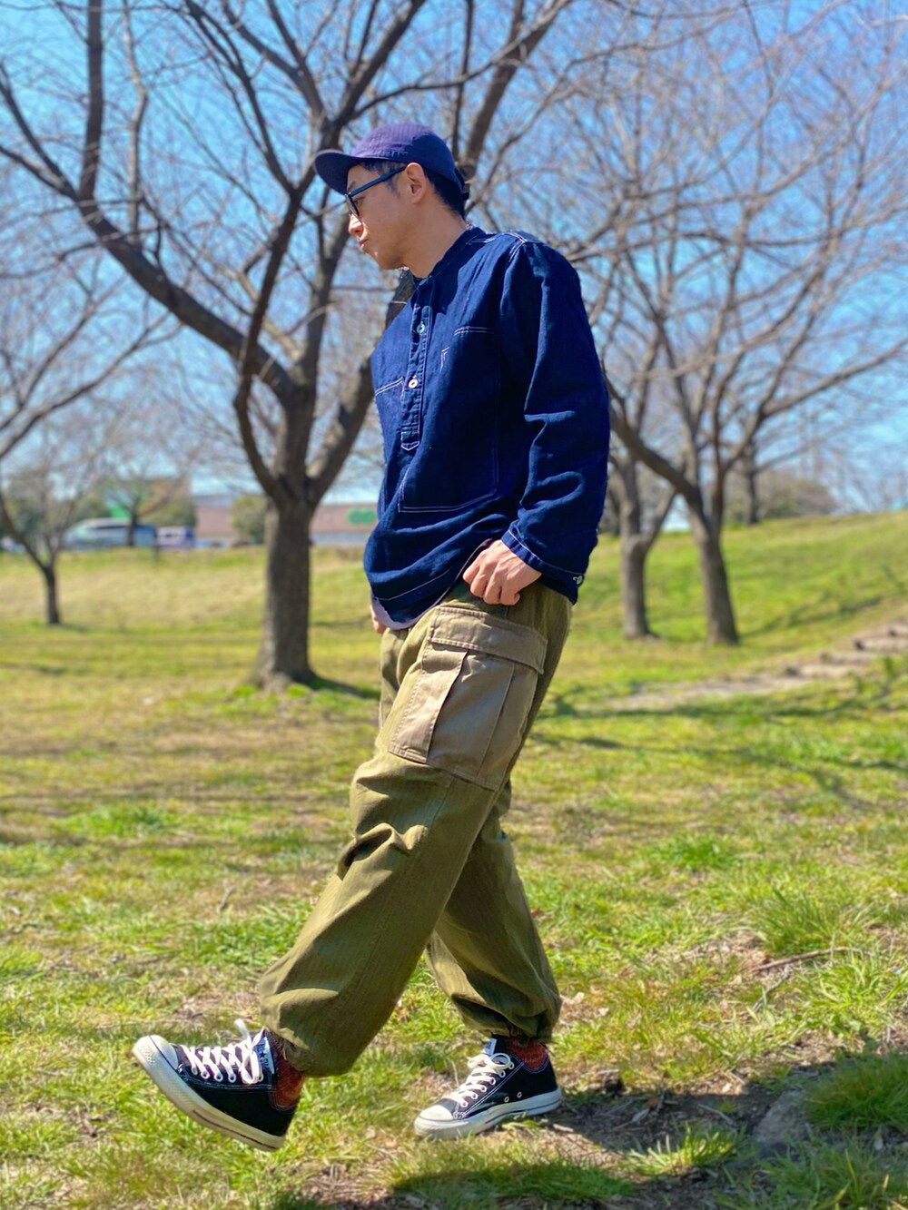 ブルー系のデニムジャケット、グリーン系のカーゴパンツ、ブラック系のスニーカーを着用したメンズの春コーディネートの2枚目の写真