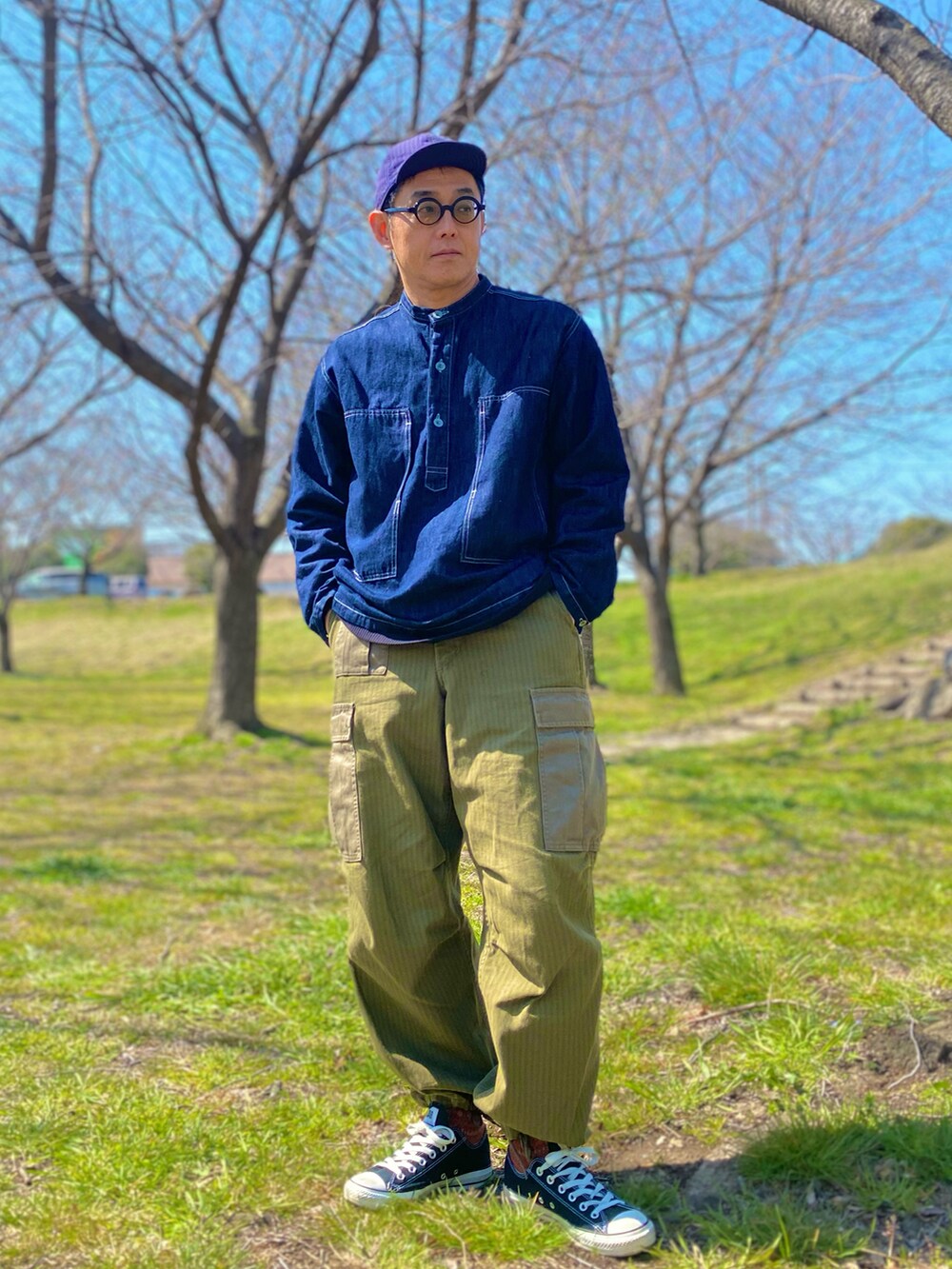 ブルー系のデニムジャケット、グリーン系のカーゴパンツ、ブラック系のスニーカーを着用したメンズの春コーディネートの3枚目の写真