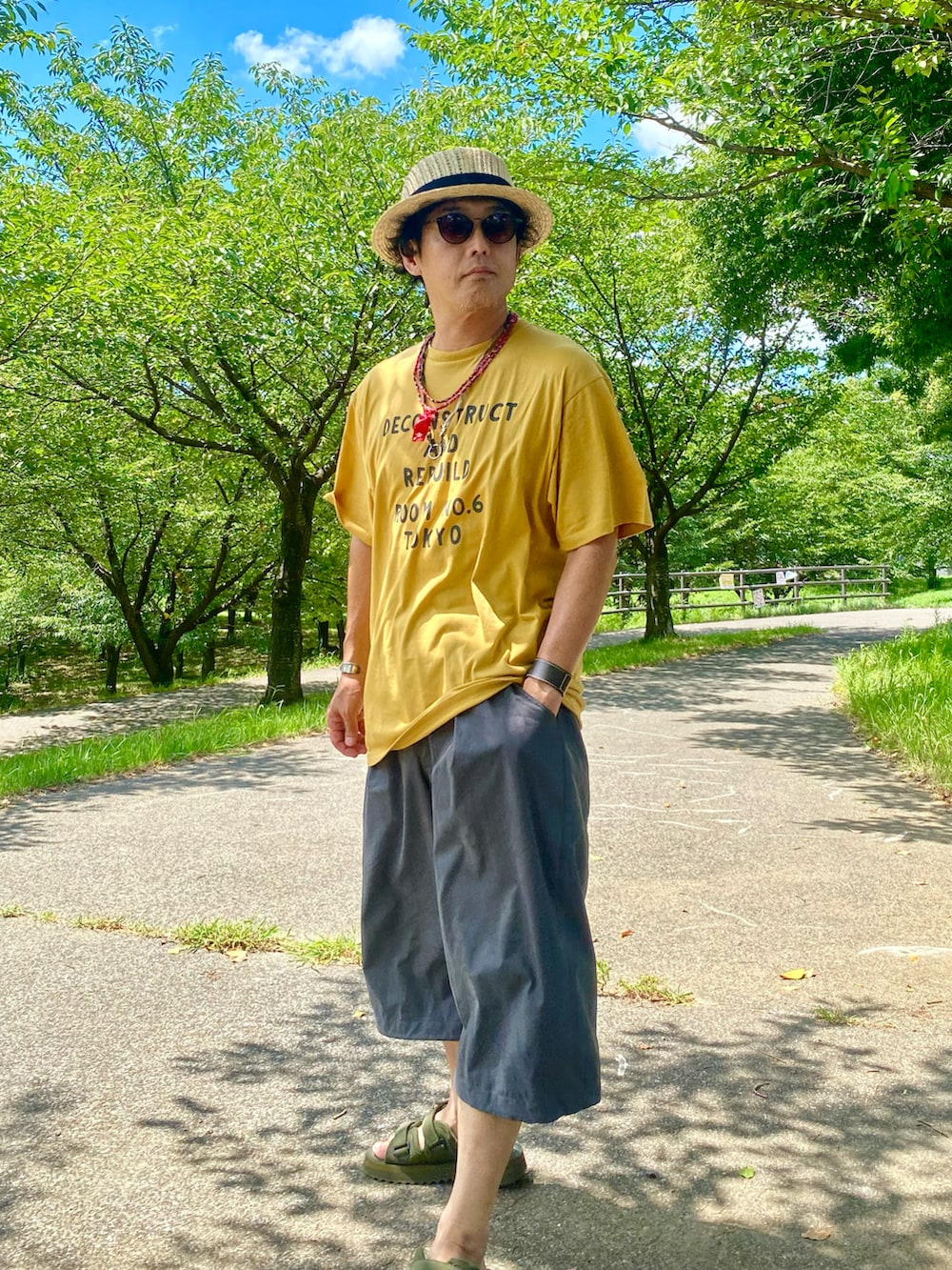 グリーン系のサンダル、ベージュ系のハットを着用したメンズの夏コーディネートの2枚目の写真