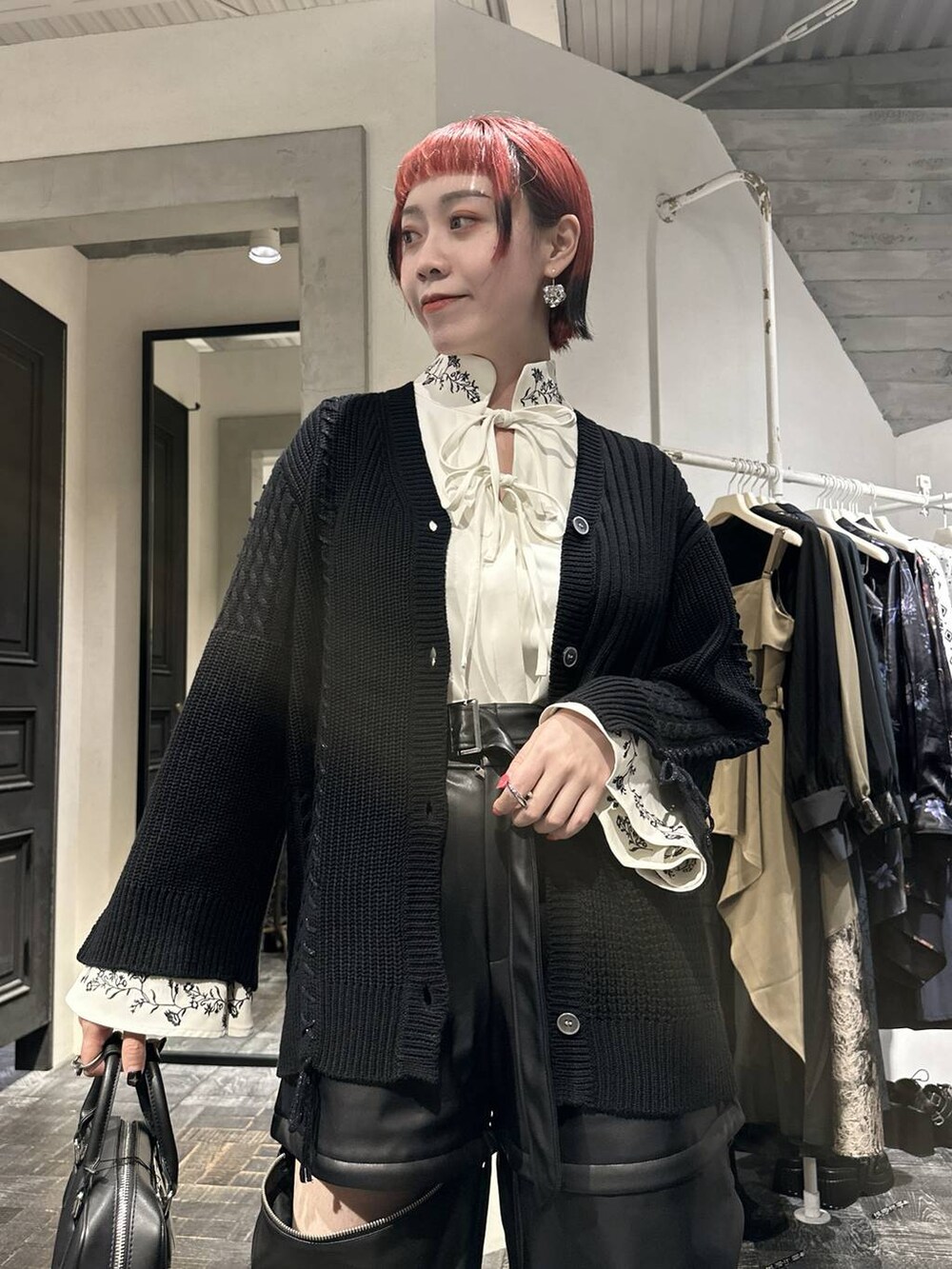 ブラック系のカーディガン/ボレロ、ブラック系のカーゴパンツ、ブラック系のブーツを着用したレディースの秋コーディネートの2枚目の写真