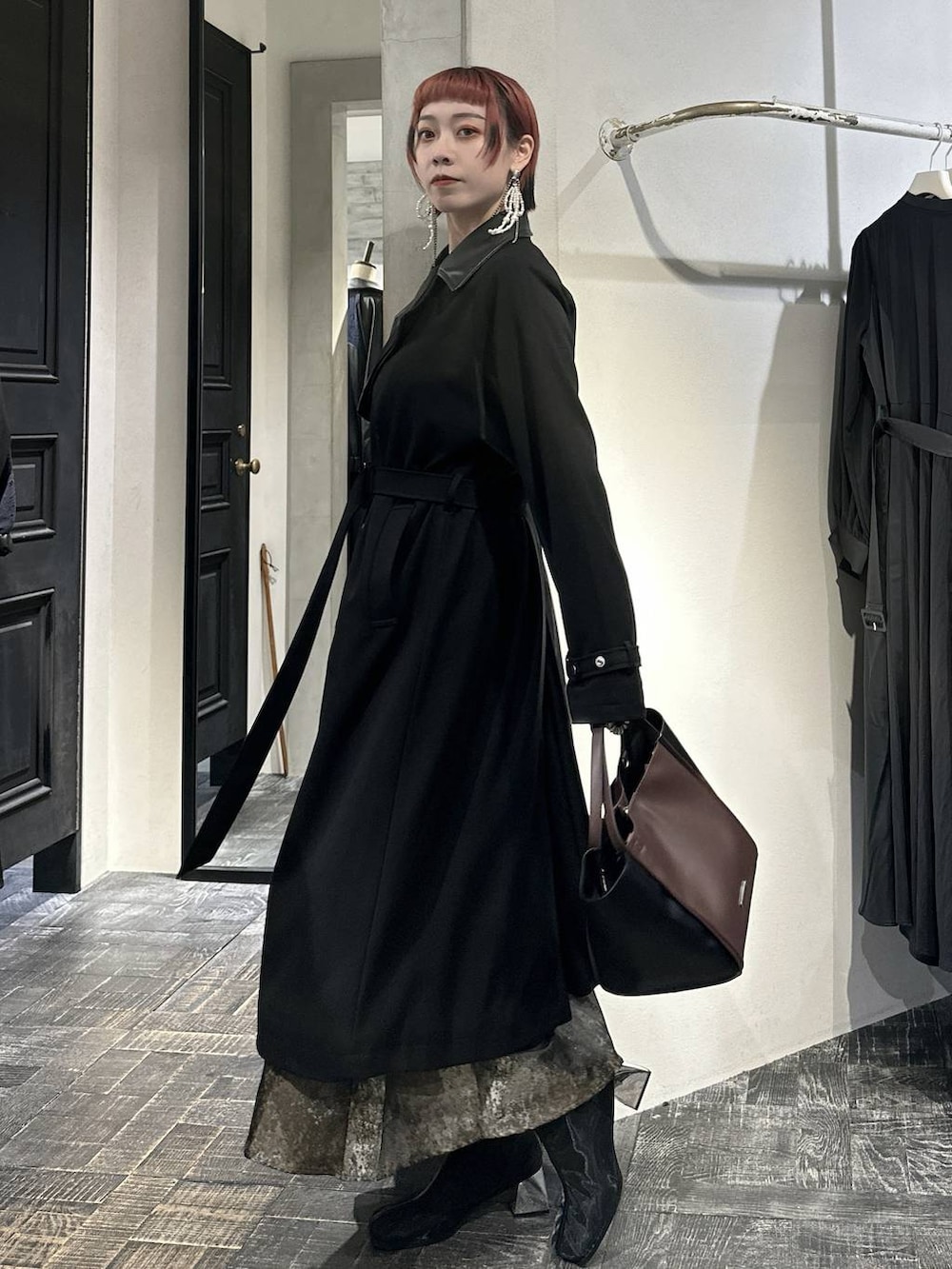 ブラウン系のスカート、ブラック系のブーツ、ブラウン系のショルダーバッグを着用したレディースの秋コーディネートの4枚目の写真