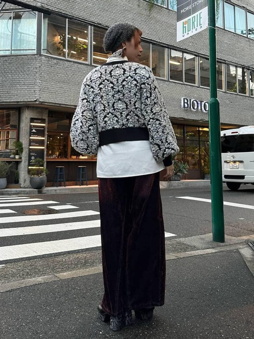 ブラック系のニット/セーター、レッド系のデニムパンツ、ホワイト系のシャツ/ブラウスを着用したレディースの秋コーディネートの3枚目の写真