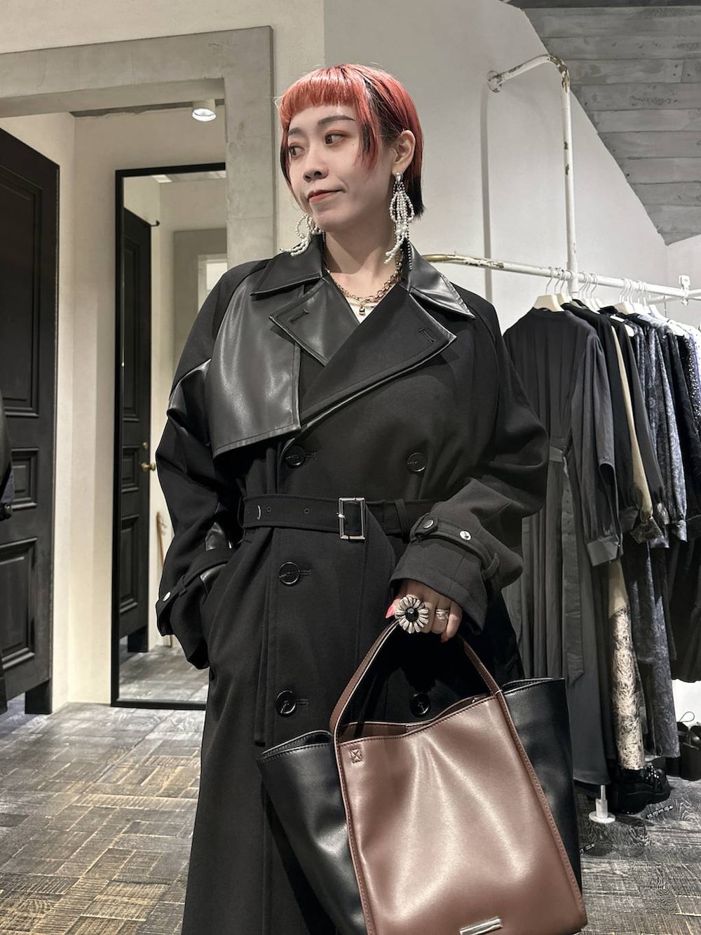 ブラウン系のスカート、ブラック系のブーツ、ブラウン系のショルダーバッグを着用したレディースの秋コーディネートの2枚目の写真