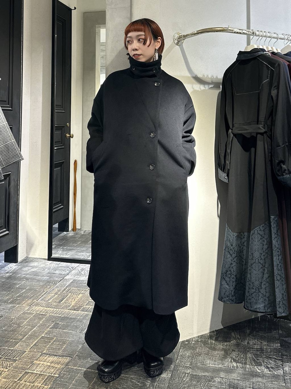 ブラック系のチェスターコート、ブルー系のニット/セーター、グレー系のブーツを着用したレディースの秋コーディネートの3枚目の写真