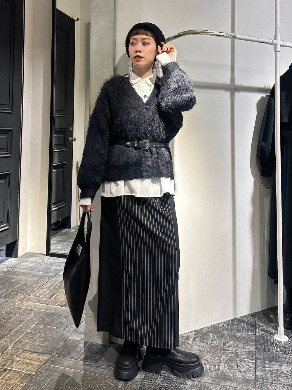 ブラック系のトートバッグ、ブラック系のカーディガン/ボレロ、ブラック系のブーツを着用したレディースの冬コーディネートの6枚目の写真