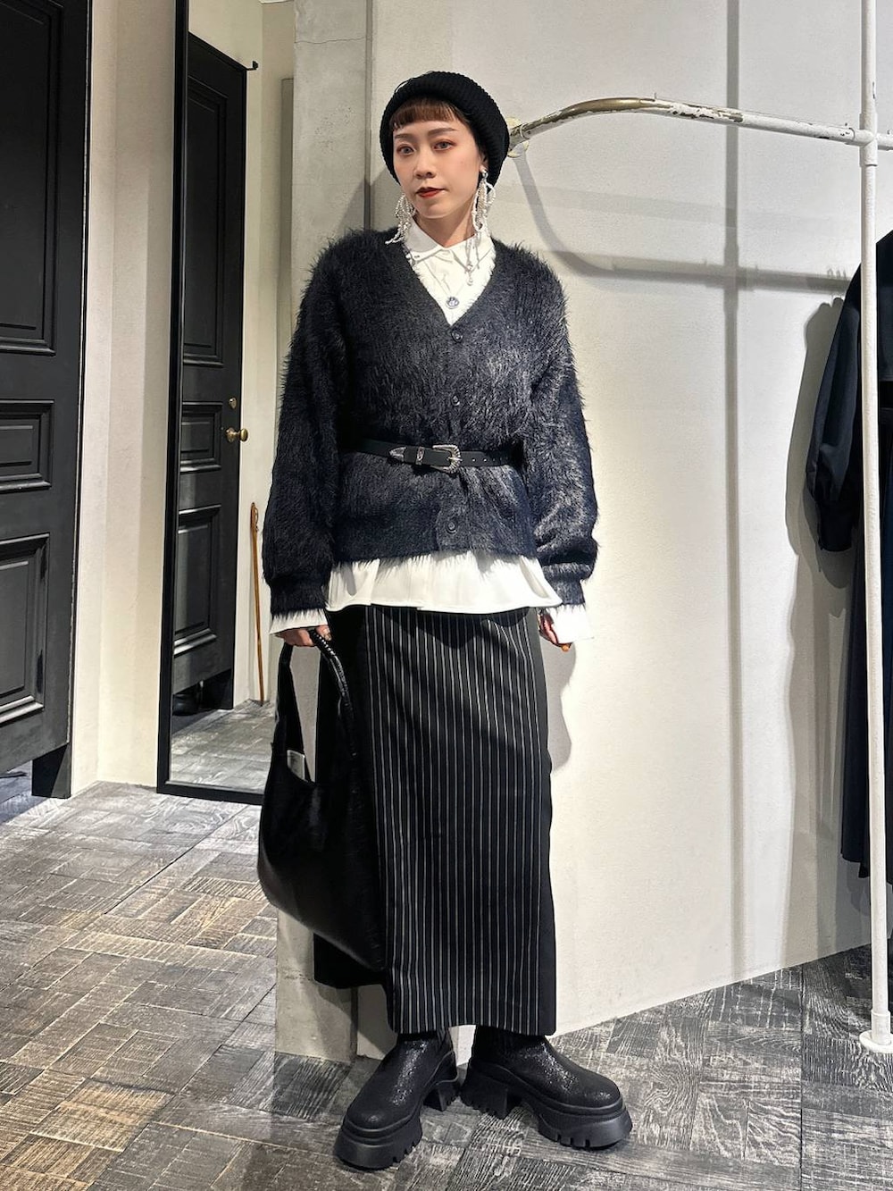 ブラック系のトートバッグ、ブラック系のカーディガン/ボレロ、ブラック系のブーツを着用したレディースの冬コーディネートの2枚目の写真