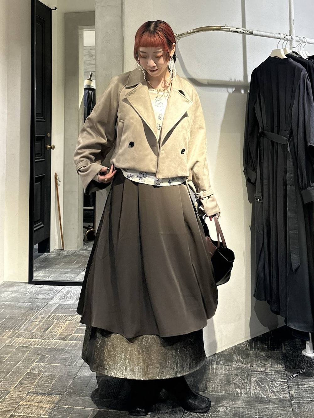 ブラウン系のスカート、ブラック系のブーツ、ブラウン系のショルダーバッグを着用したレディースの秋コーディネートの3枚目の写真