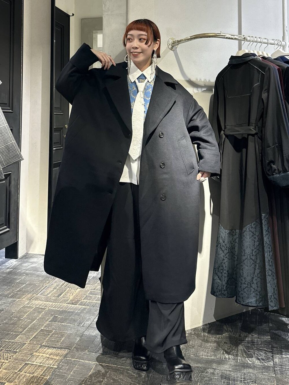 ブラック系のチェスターコート、ブルー系のニット/セーター、グレー系のブーツを着用したレディースの秋コーディネートの7枚目の写真