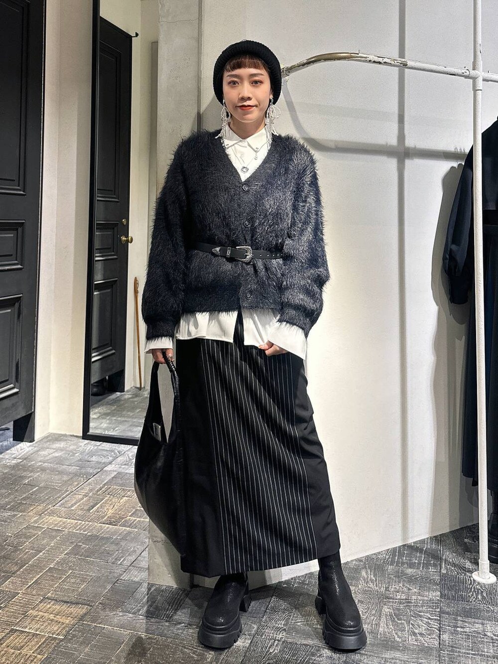 ブラック系のトートバッグ、ブラック系のカーディガン/ボレロ、ブラック系のブーツを着用したレディースの冬コーディネートの7枚目の写真