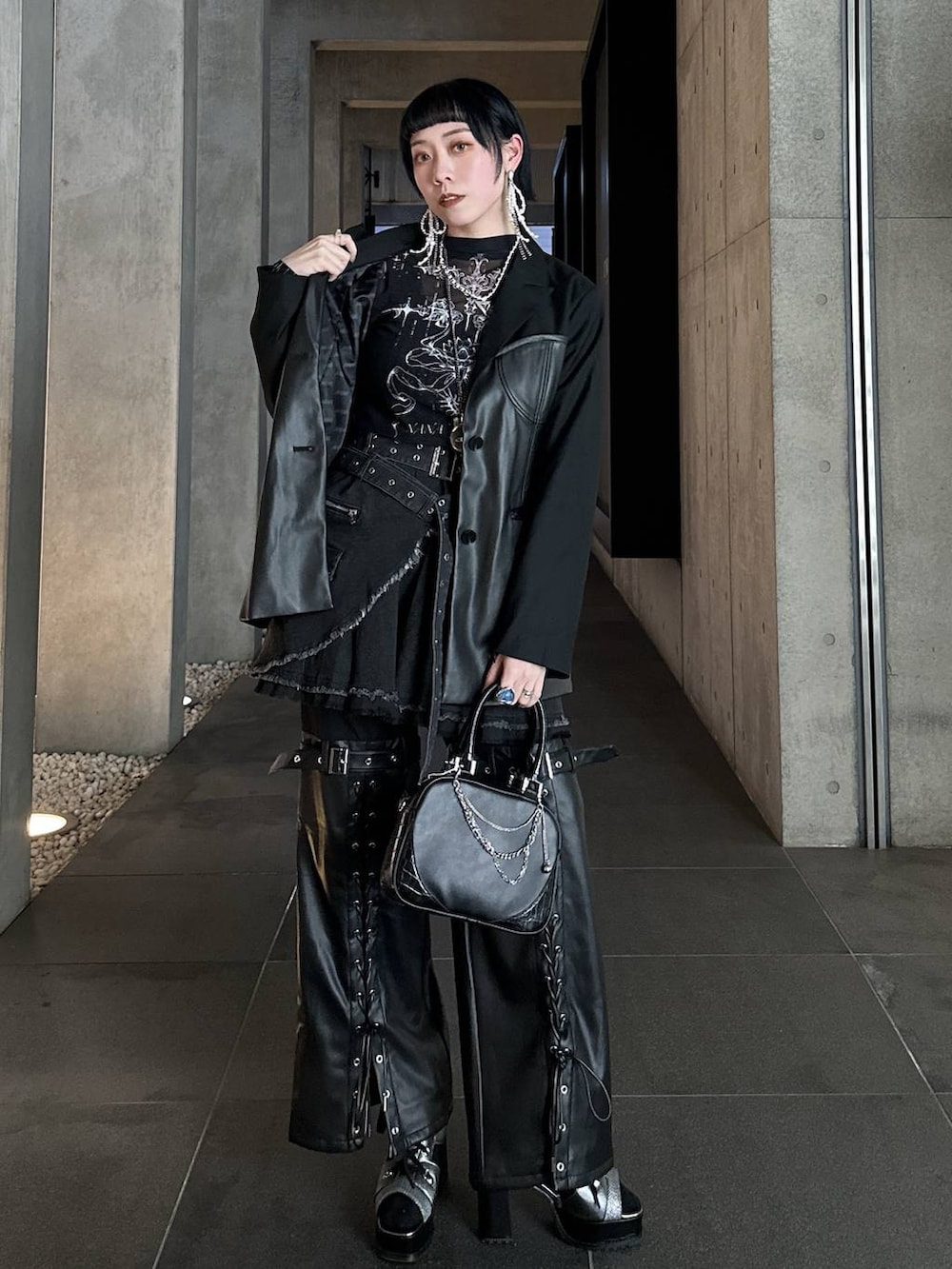 シルバー系のブーツ、ブラック系のショルダーバッグ、シルバー系のネックレスを着用したレディースの春コーディネートの2枚目の写真