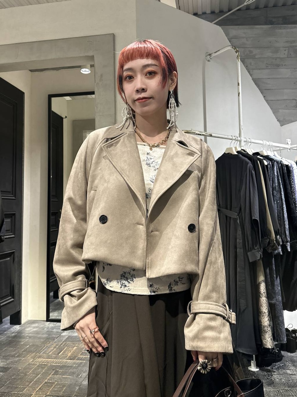 ブラウン系のスカート、ブラック系のブーツ、ブラウン系のショルダーバッグを着用したレディースの秋コーディネートの2枚目の写真