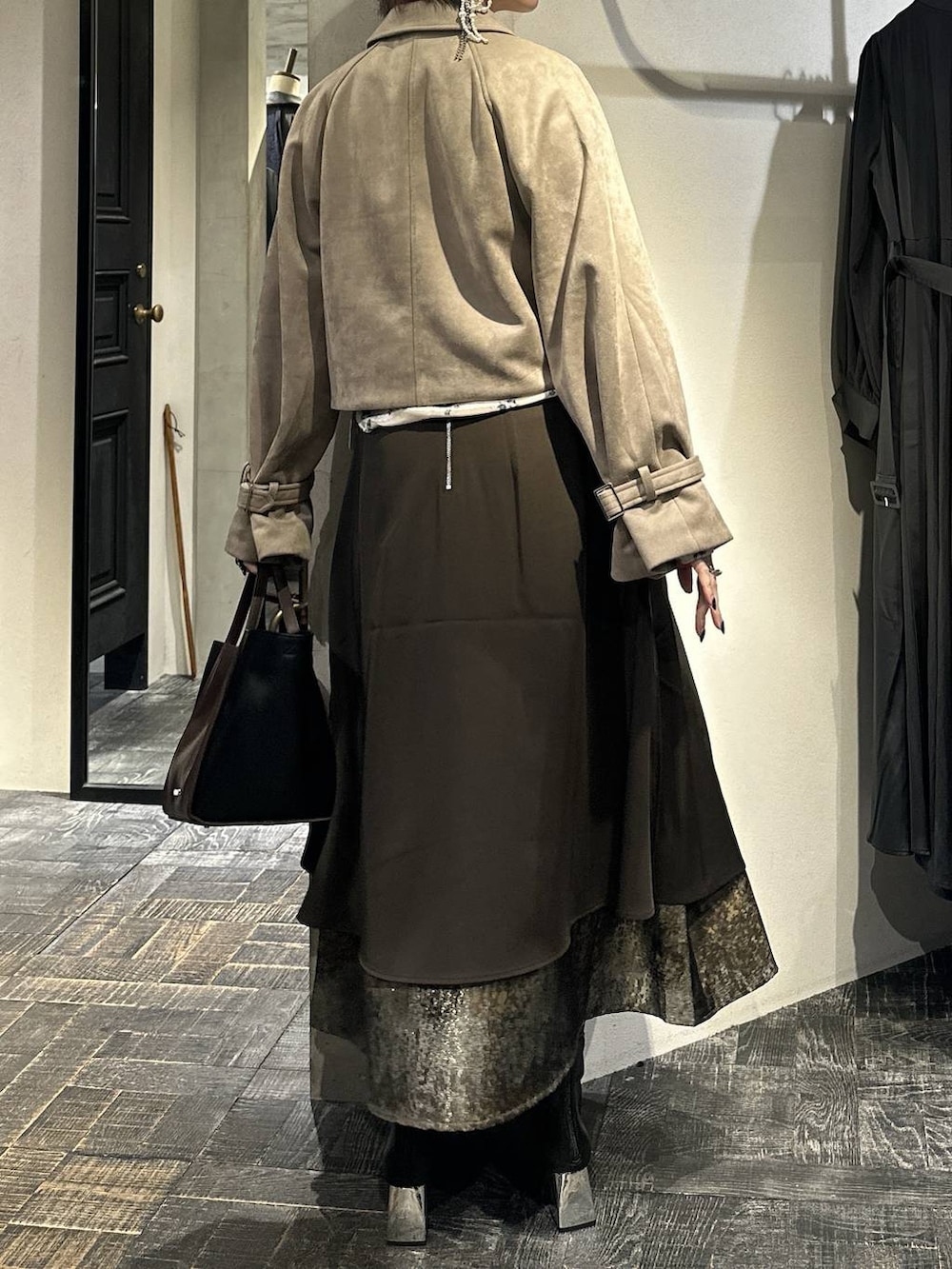 ブラウン系のスカート、ブラック系のブーツ、ブラウン系のショルダーバッグを着用したレディースの秋コーディネートの4枚目の写真