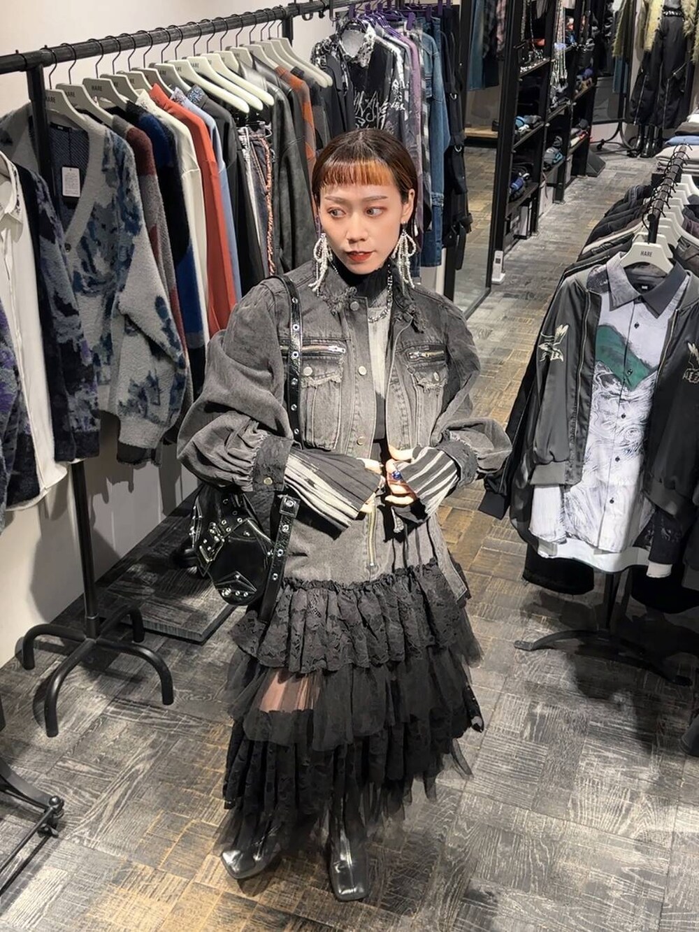 シルバー系のブーツ、ブラック系のニット/セーター、ブラック系のショルダーバッグを着用したレディースの秋コーディネートの2枚目の写真