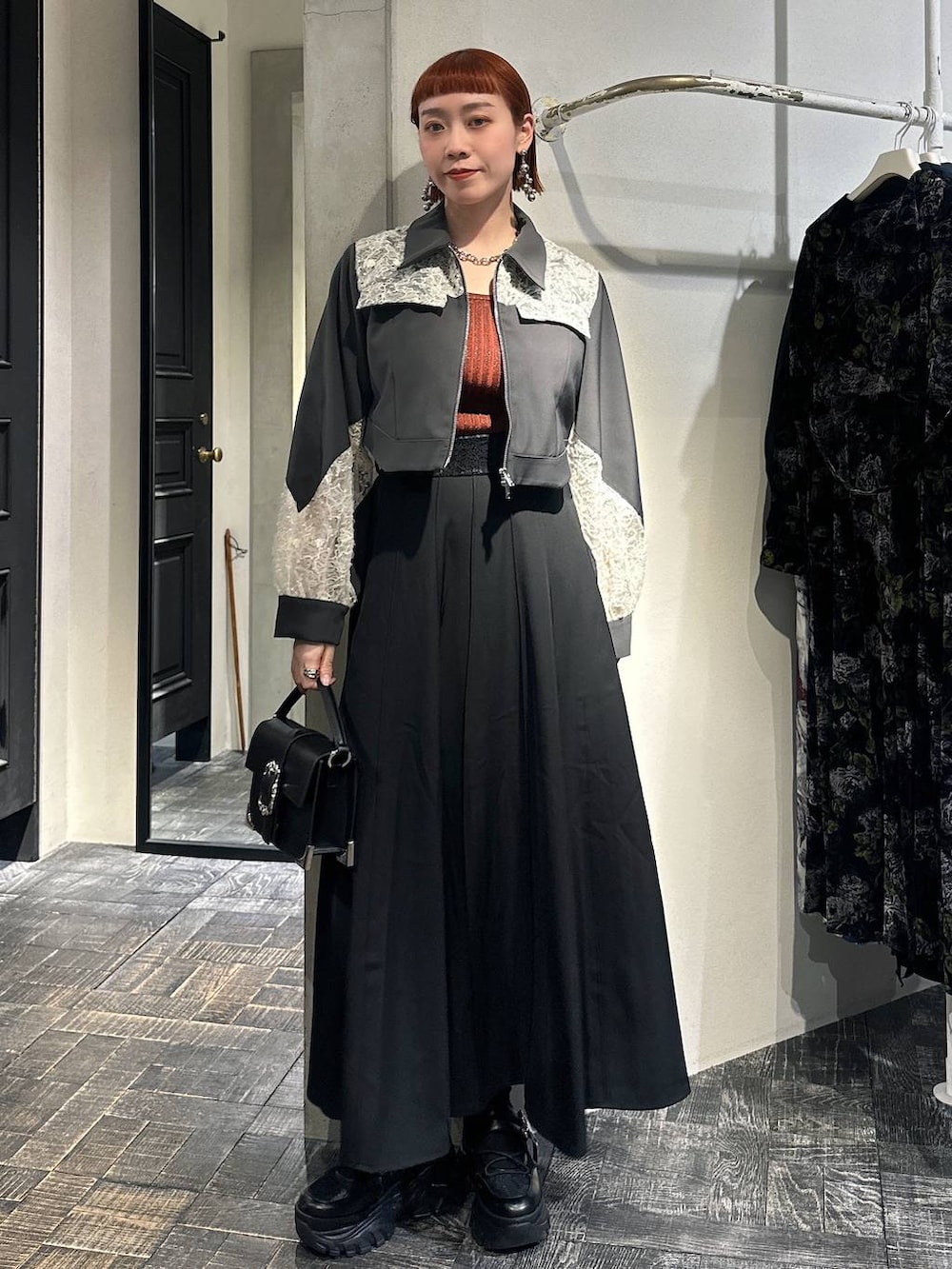 オレンジ系のタンクトップ、ブラック系のショルダーバッグ、ブラック系のスニーカーを着用したレディースの冬コーディネートの2枚目の写真