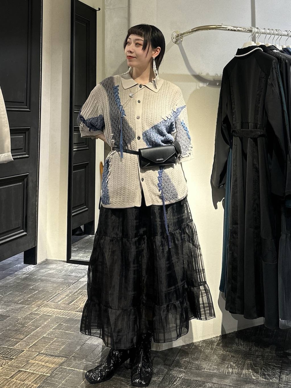 ブラック系のブーツ、ブラック系のボディバッグ/ウエストポーチ、ブラック系のスカートを着用したレディースの春コーディネートの6枚目の写真