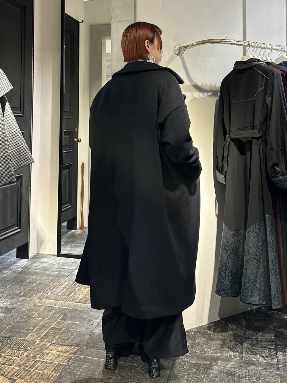 ブラック系のチェスターコート、ブルー系のニット/セーター、グレー系のブーツを着用したレディースの秋コーディネートの6枚目の写真