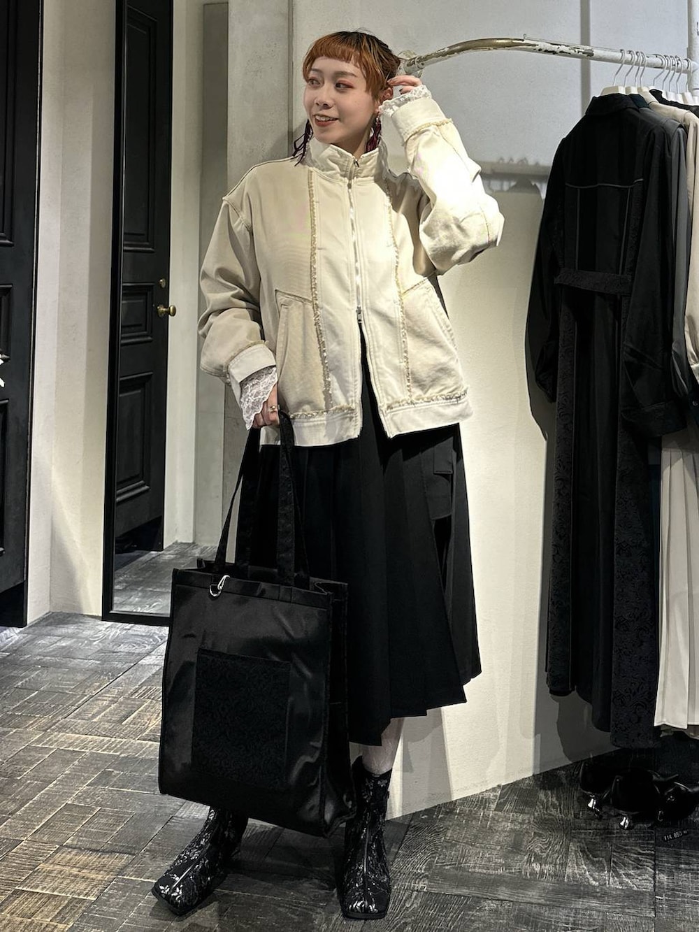 ブラック系のトートバッグ、ブラック系のブーツ、ブラック系のスカートを着用したレディースの冬コーディネートの3枚目の写真