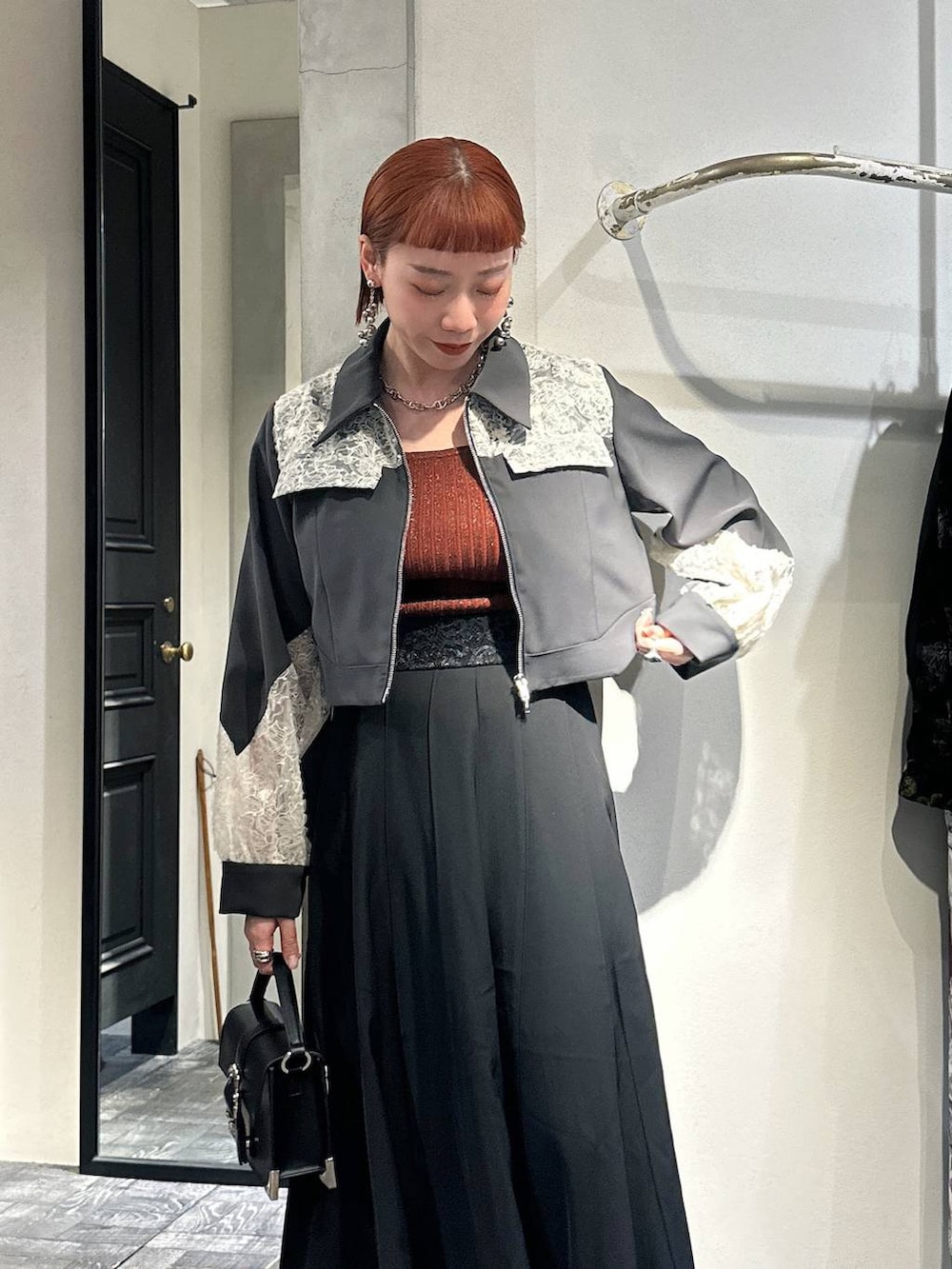 オレンジ系のタンクトップ、ブラック系のショルダーバッグ、ブラック系のスニーカーを着用したレディースの冬コーディネートの3枚目の写真