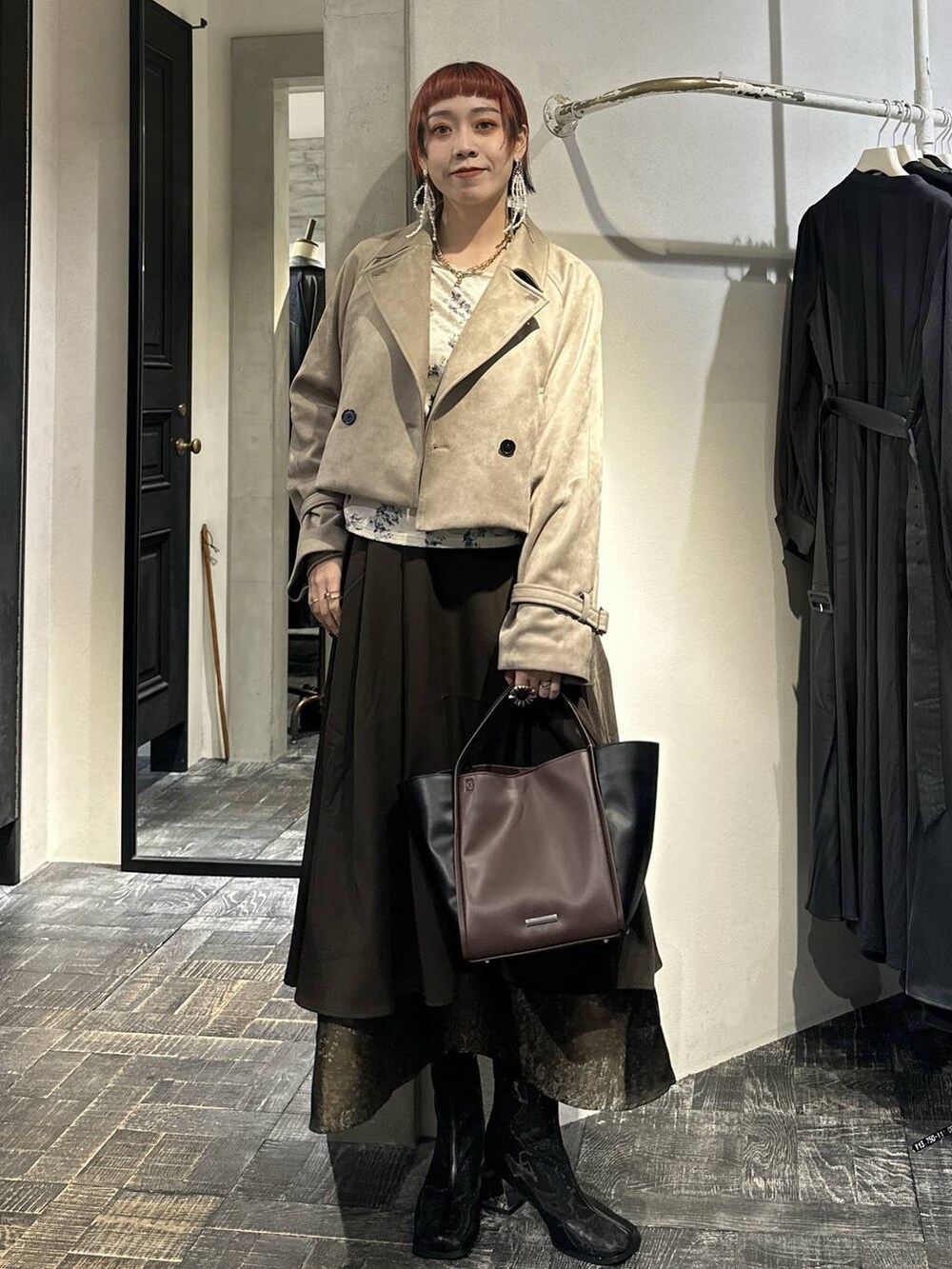 ブラウン系のスカート、ブラック系のブーツ、ブラウン系のショルダーバッグを着用したレディースの秋コーディネートの5枚目の写真