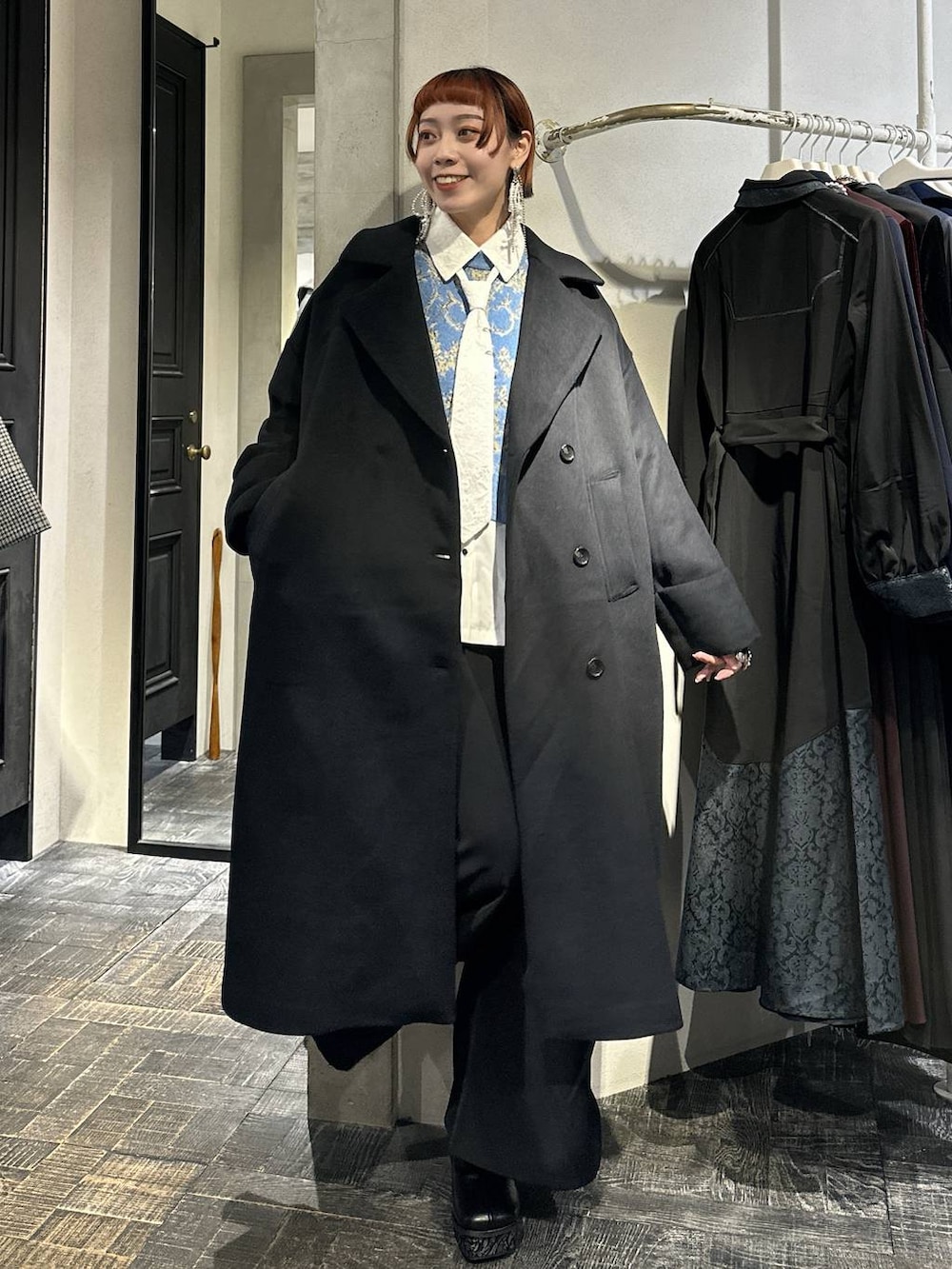 ブラック系のチェスターコート、ブルー系のニット/セーター、グレー系のブーツを着用したレディースの秋コーディネートの8枚目の写真