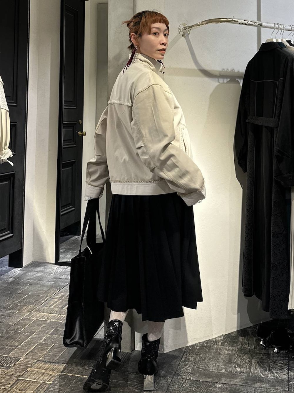 ブラック系のトートバッグ、ブラック系のブーツ、ブラック系のスカートを着用したレディースの冬コーディネートの6枚目の写真