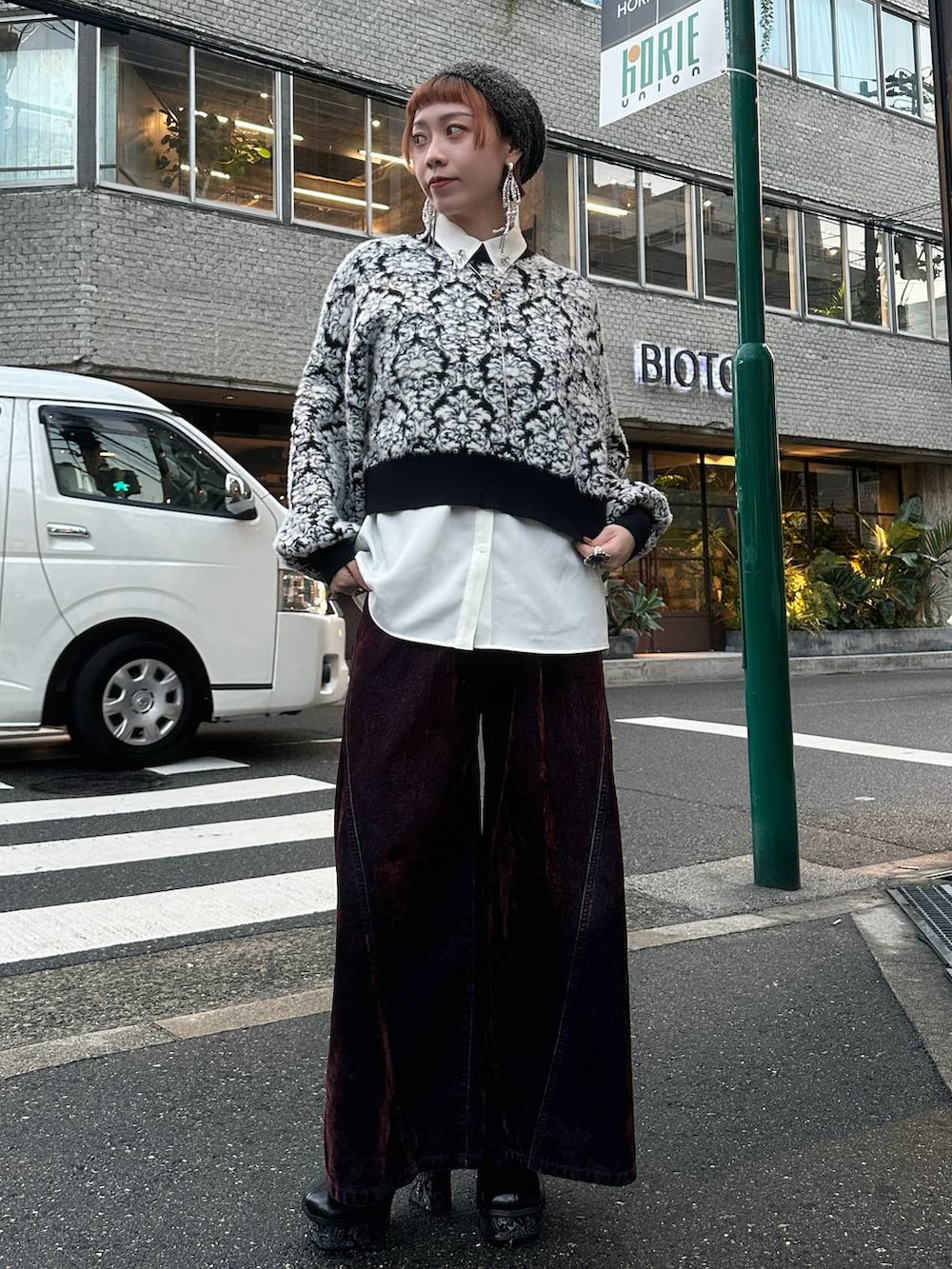 ブラック系のニット/セーター、レッド系のデニムパンツ、ホワイト系のシャツ/ブラウスを着用したレディースの秋コーディネートの2枚目の写真