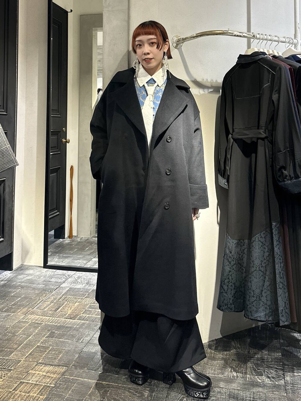 ブラック系のチェスターコート、ブルー系のニット/セーター、グレー系のブーツを着用したレディースの秋コーディネートの4枚目の写真