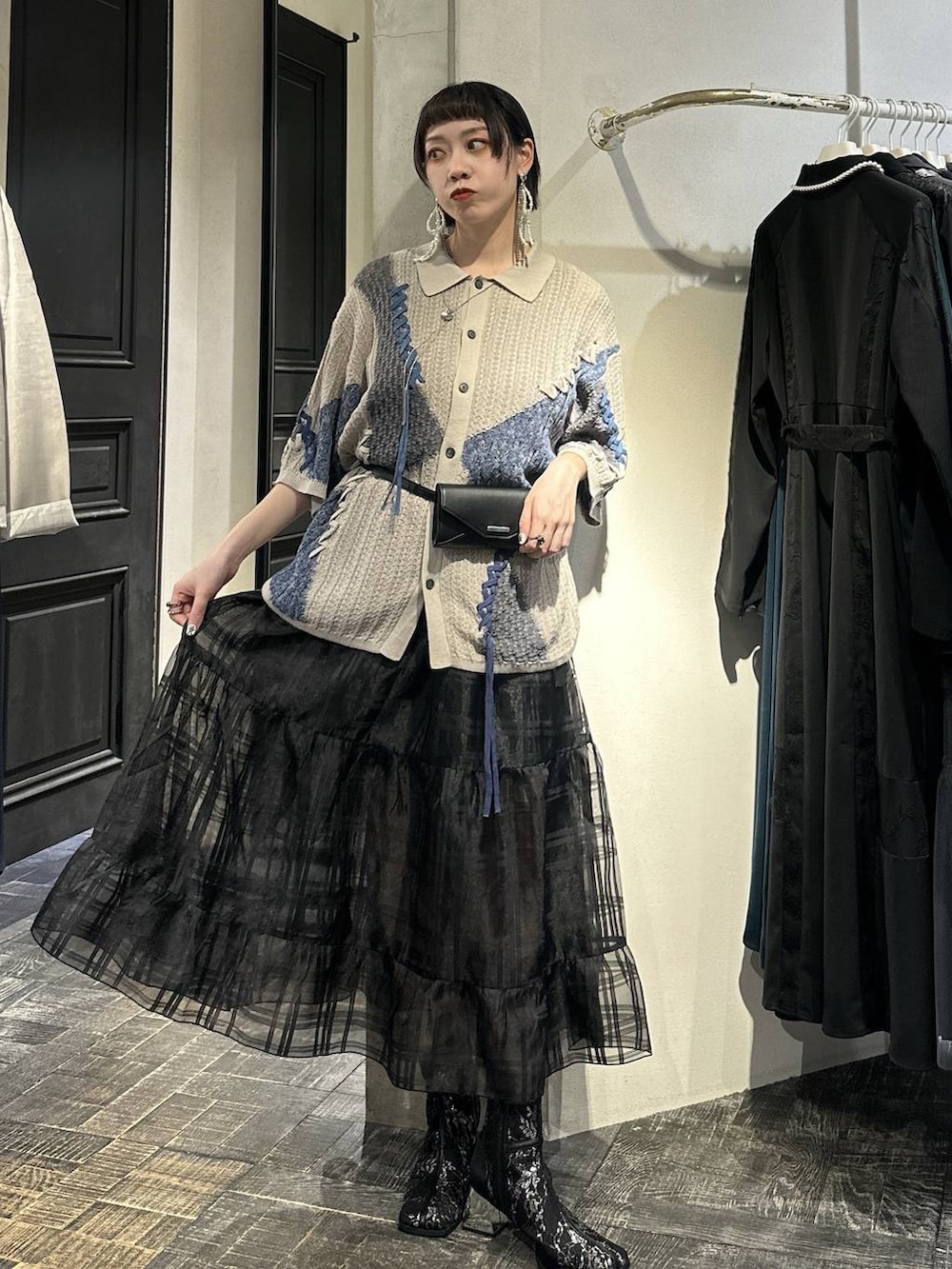 ブラック系のブーツ、ブラック系のボディバッグ/ウエストポーチ、ブラック系のスカートを着用したレディースの春コーディネートの3枚目の写真