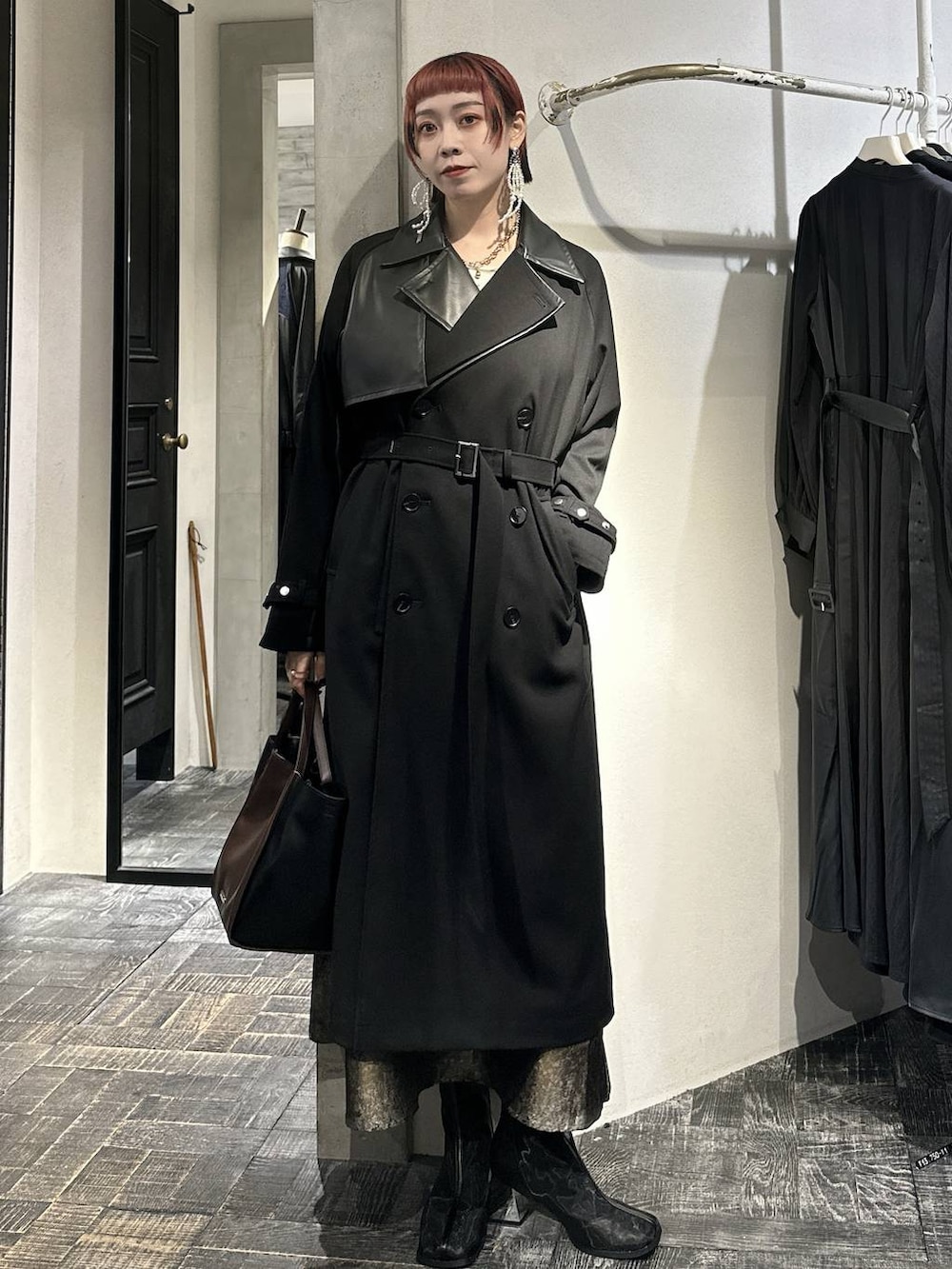 ブラウン系のスカート、ブラック系のブーツ、ブラウン系のショルダーバッグを着用したレディースの秋コーディネートの3枚目の写真