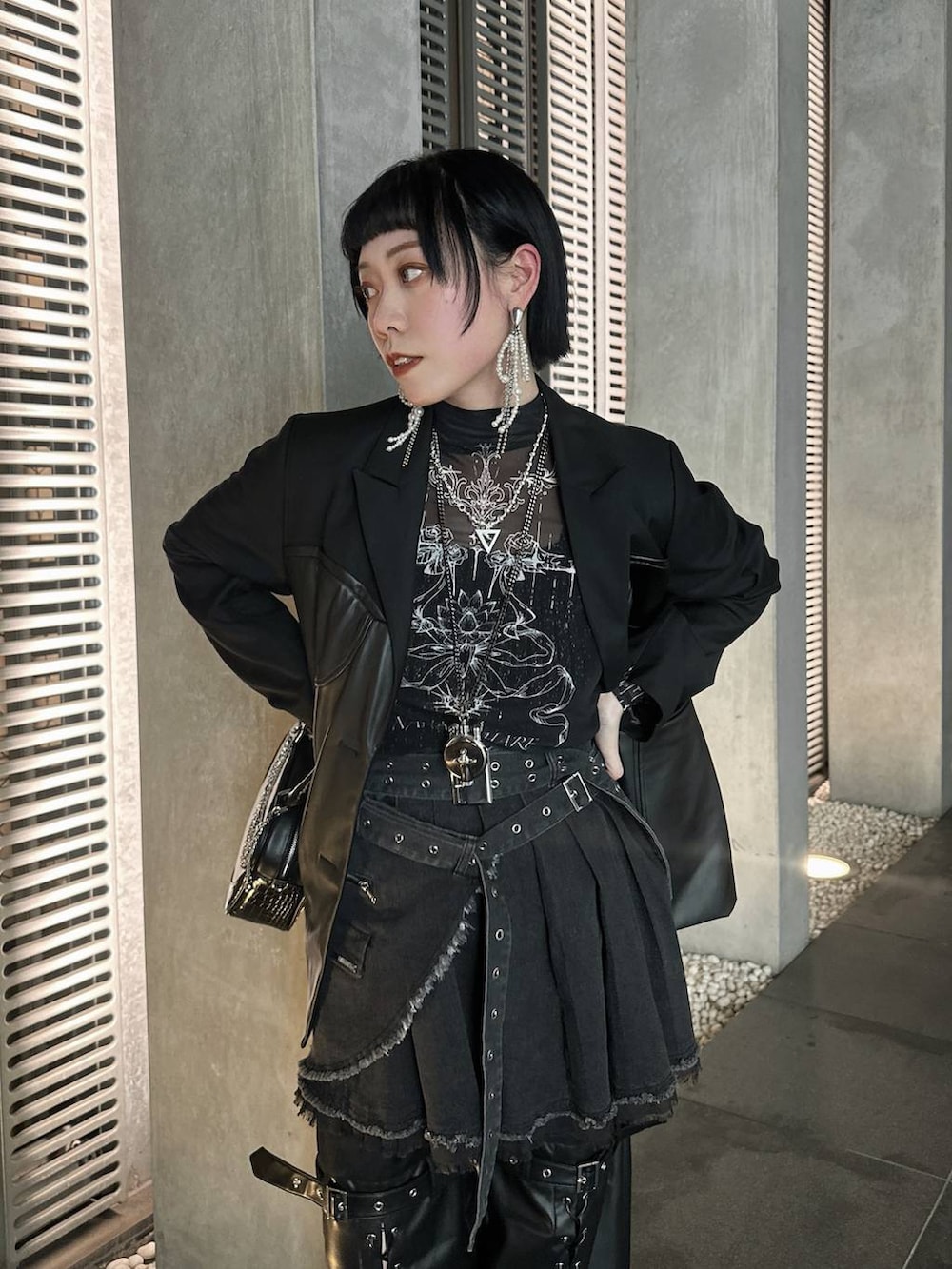 シルバー系のブーツ、ブラック系のショルダーバッグ、シルバー系のネックレスを着用したレディースの春コーディネートの4枚目の写真