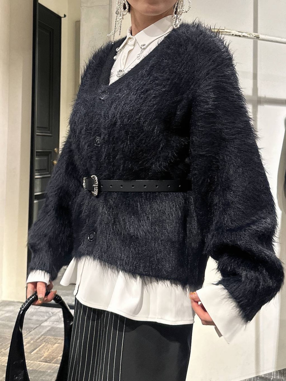 ブラック系のトートバッグ、ブラック系のカーディガン/ボレロ、ブラック系のブーツを着用したレディースの冬コーディネートの4枚目の写真