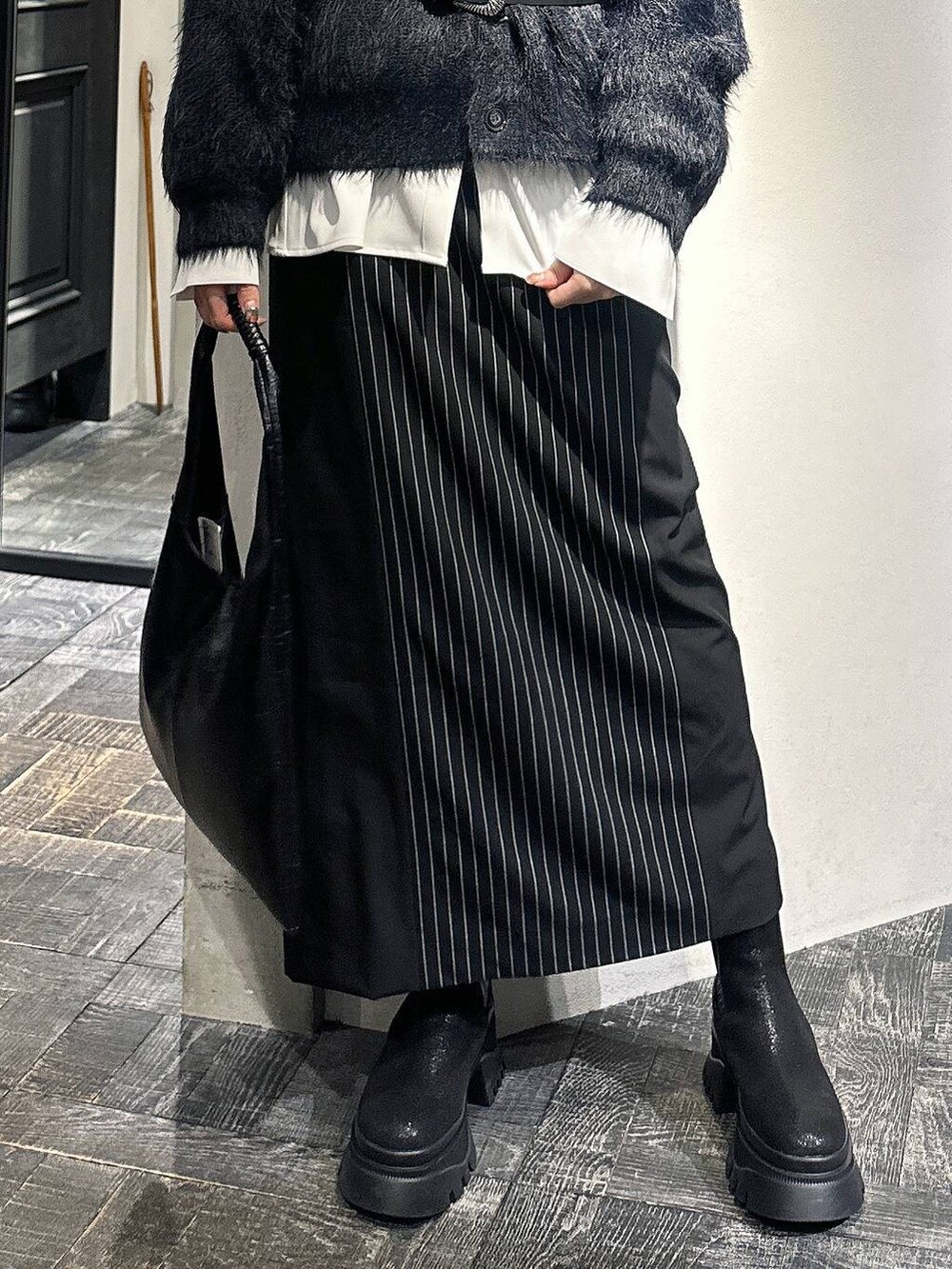 ブラック系のトートバッグ、ブラック系のカーディガン/ボレロ、ブラック系のブーツを着用したレディースの冬コーディネートの5枚目の写真