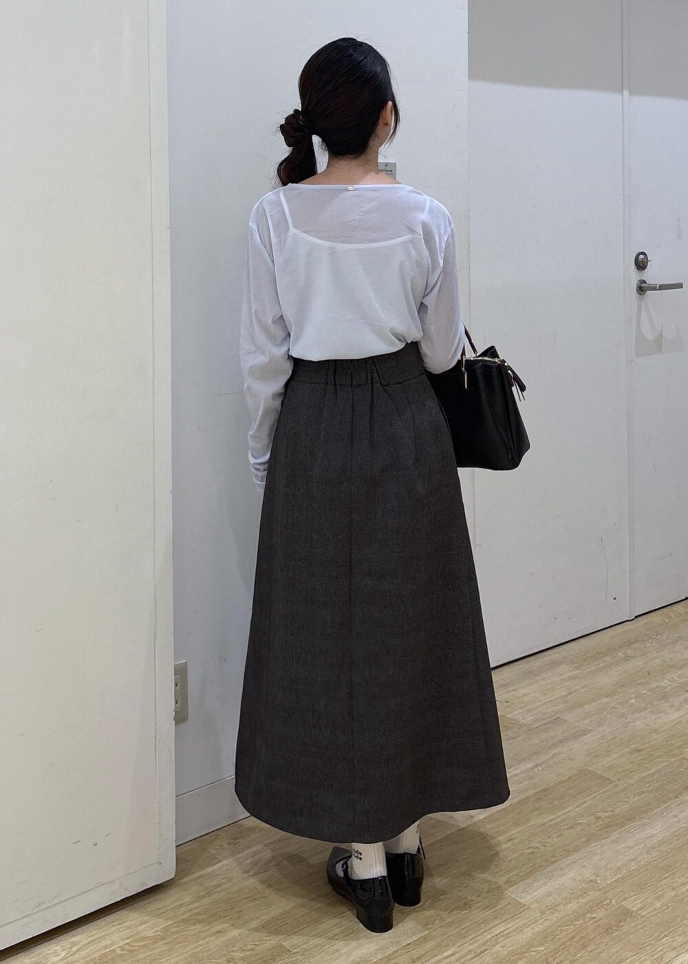 ブラック系のパンプス、ブラック系のトートバッグ、ブラウン系のスカートを着用したレディースの秋コーディネートの4枚目の写真