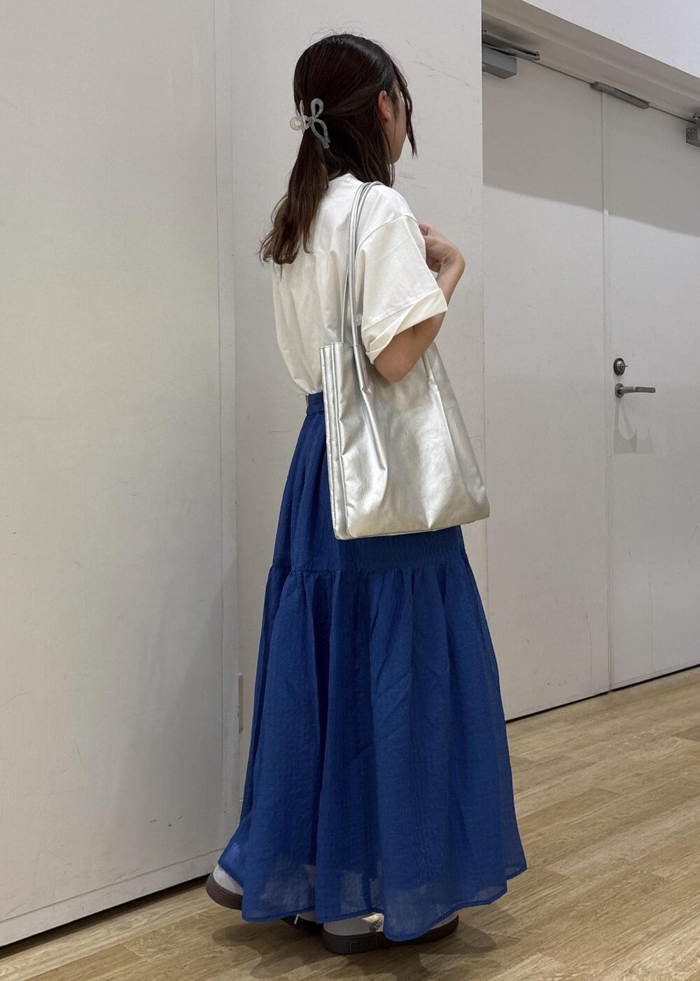 シルバー系のトートバッグ、ブルー系のスカート、ホワイト系のTシャツ/カットソーを着用したレディースの夏コーディネートの4枚目の写真