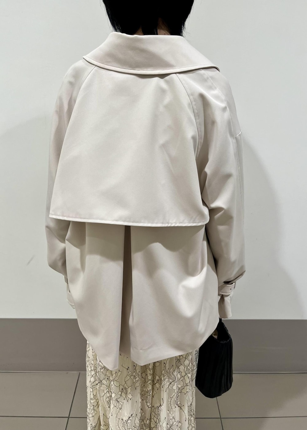 ブラック系のローファー、ホワイト系のスカート、ベージュ系のトレンチコートを着用したレディースの春コーディネートの5枚目の写真