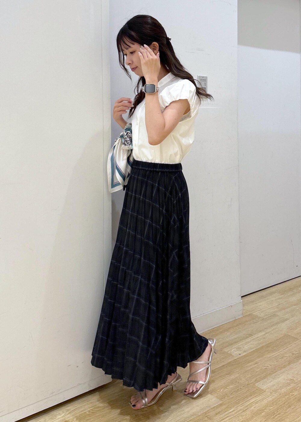 シルバー系のサンダル、ブラック系のショルダーバッグ、グリーン系のスカートを着用したレディースの夏コーディネートの2枚目の写真