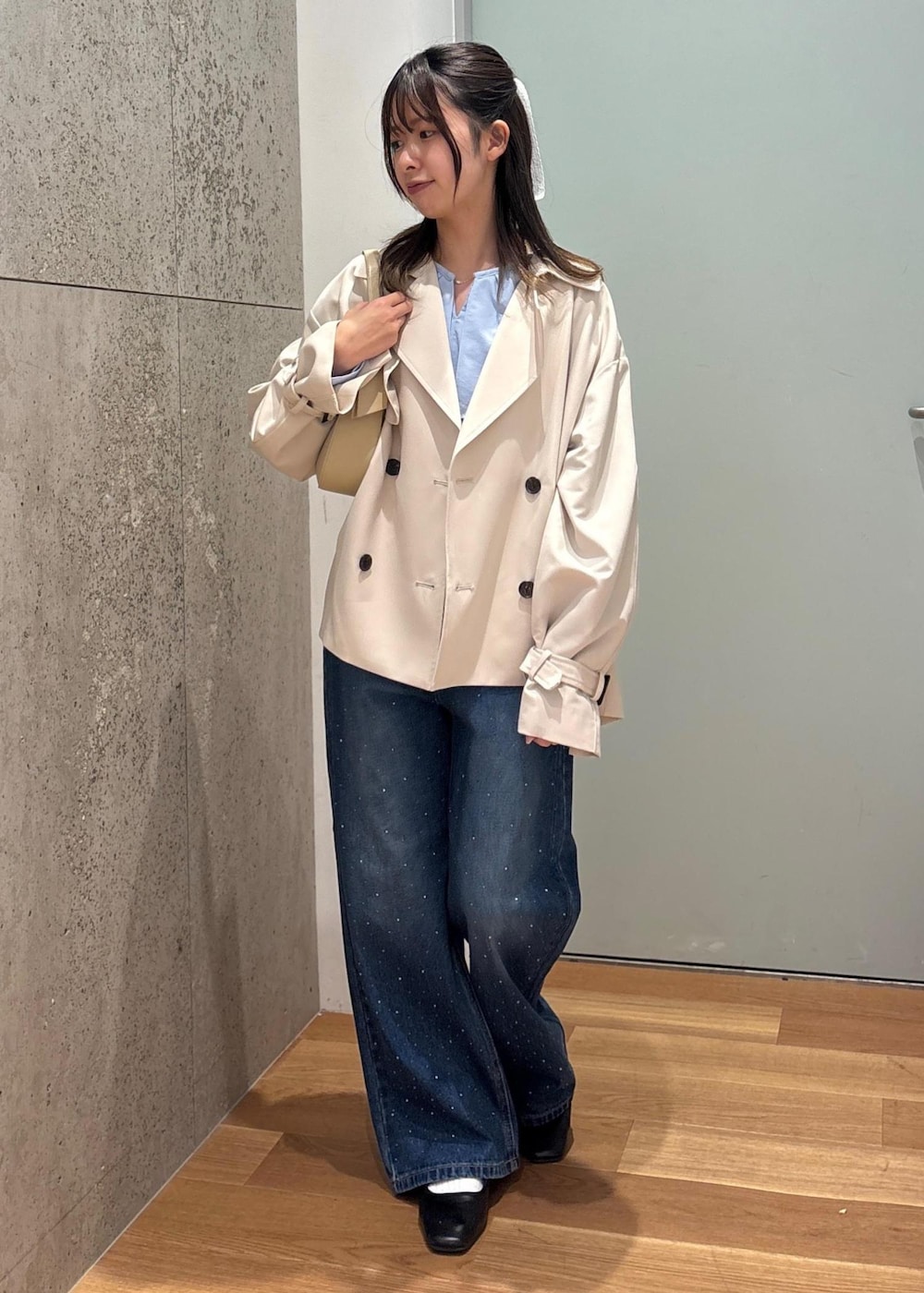 ベージュ系のハンドバッグ、ブルー系のデニムパンツ、ブルー系のシャツ/ブラウスを着用したレディースの春コーディネートの2枚目の写真
