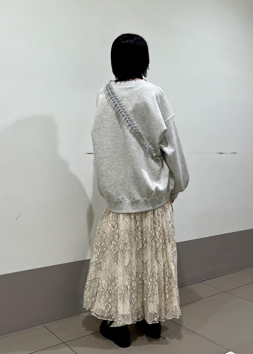 ブラック系のローファー、グレー系のスウェット、ホワイト系のスカートを着用したレディースの春コーディネートの2枚目の写真