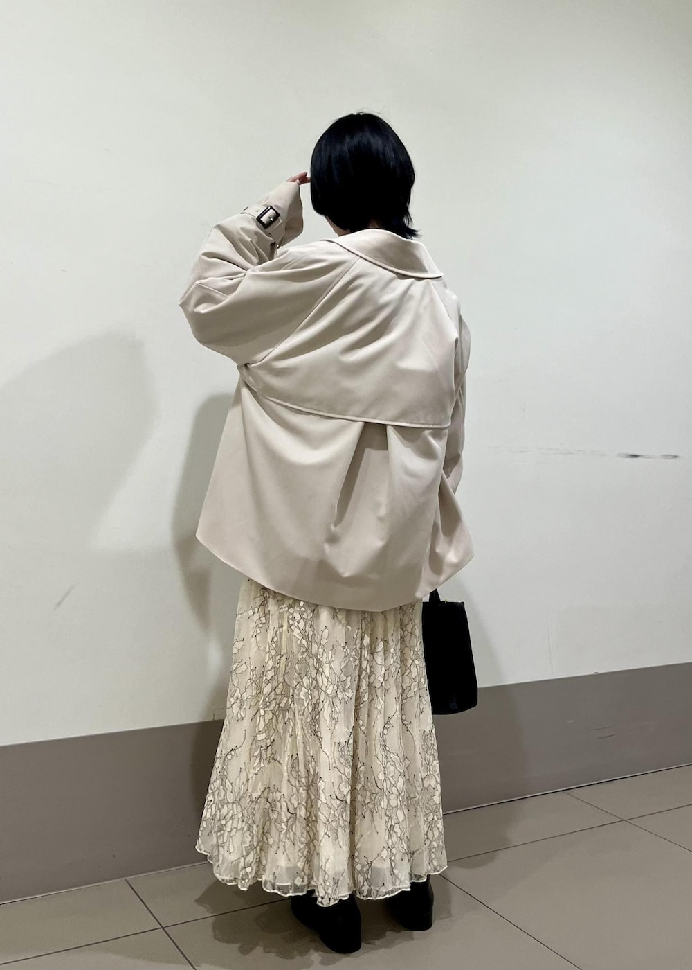 ブラック系のローファー、ホワイト系のスカート、ベージュ系のトレンチコートを着用したレディースの春コーディネートの2枚目の写真