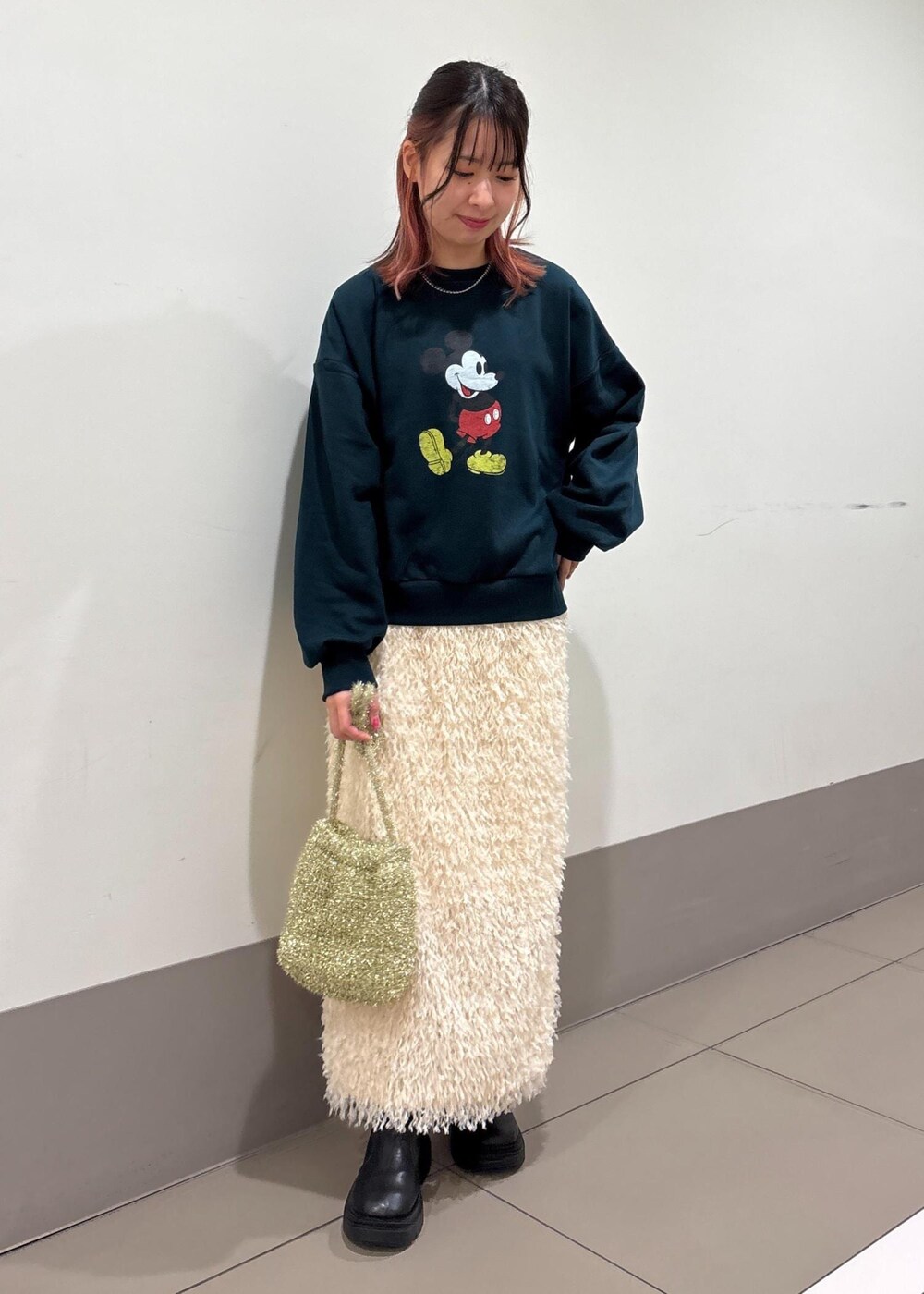 ホワイト系のスカート、ゴールド系のショルダーバッグ、グリーン系のスウェットを着用したレディースの冬コーディネートの2枚目の写真